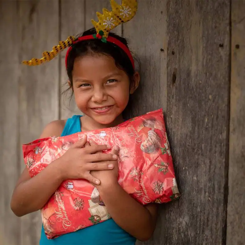 A girl hugging a wrapped Christmas gift