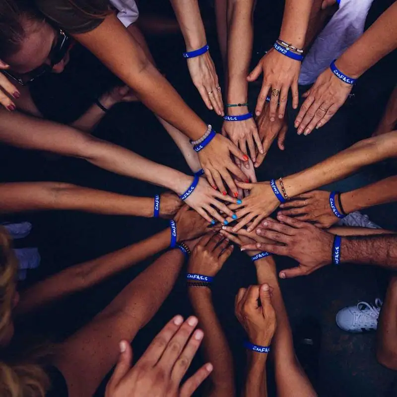 Many hands joined in the centre of a circle
